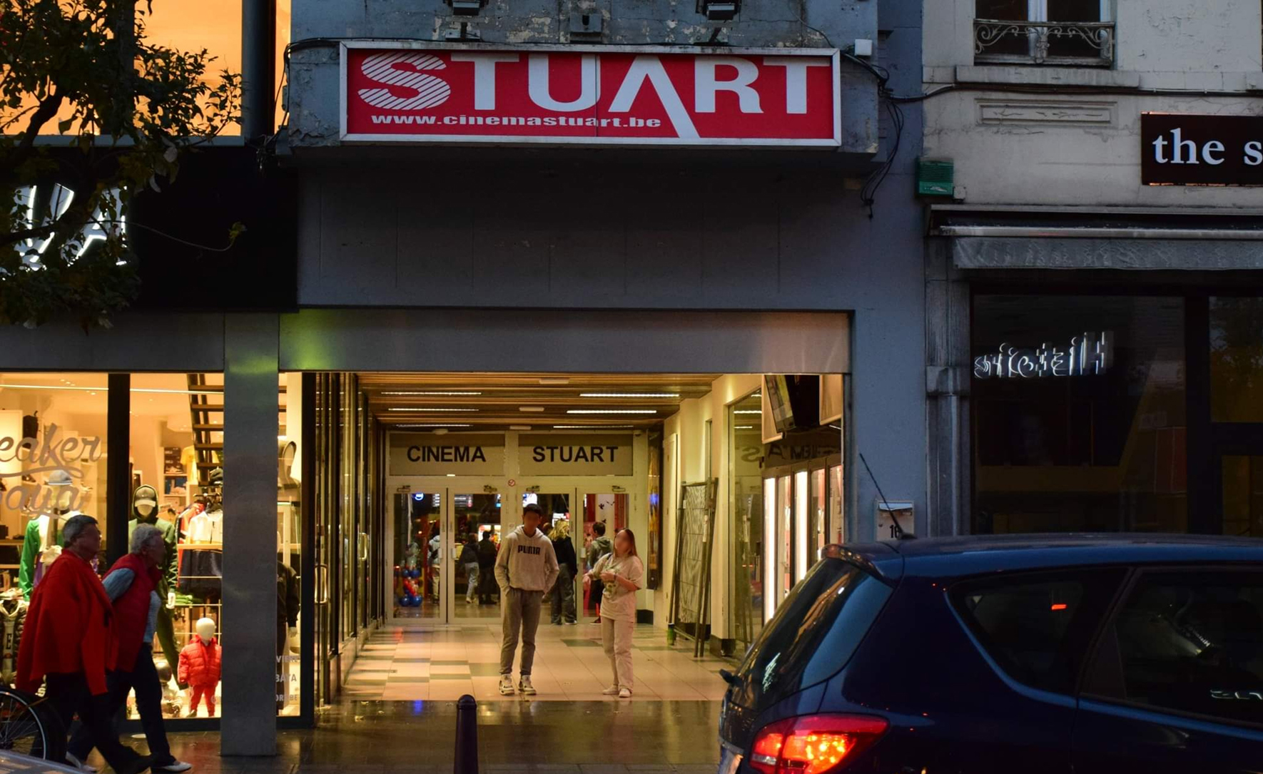 Ingang van bioscoop Stuart met voetgangers in avondlicht.