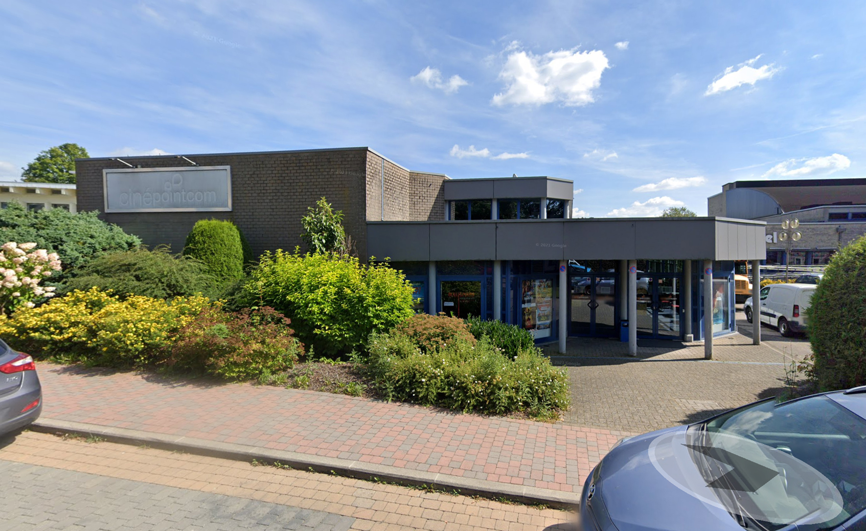 Gevel van bioscoop met struiken op parking.